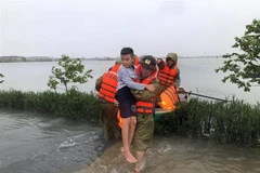 Lực lượng công an huyện Thạch Hà, tỉnh Hà Tĩnh sơ tán người già, trẻ em đến nơi an toàn. (Ảnh: TTXVN phát)