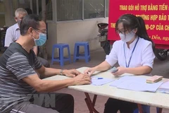 Trao tiền hỗ trợ cho các đối tượng gặp khó khăn do dịch bệnh COVID-19 theo tinh thần Nghị quyết 42 của Chính phủ. (Ảnh minh họa. Nguồn: TTXVN)