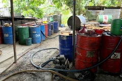 Số nhớt thải chuẩn bị được tái chế bị cơ quan công an thu giữ. (Ảnh: Công Mạo/TTXVN)