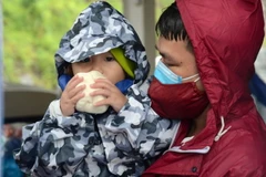 Người về quê tranh thủ nghỉ chân, ăn đồ ăn miễn phí trước khi tiếp tục lên đường. (Ảnh: Quốc Dũng/TTXVN)