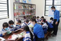 Các anh chị đoàn viên TTXVN hướng dẫn học sinh Điểm trường Văn La tra cứu thông tin bổ ích từ Tủ sách Đinh Hữu Dư. (Ảnh: Hoàng Nguyên/TTXVN)