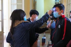 Đo thân nhiệt cho học sinh trước khi vào lớp. (Ảnh: Tường Vi/TTXVN)
