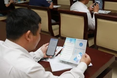 Một đại biểu tìm hiểu cách cài đặt ứng dụng VssID trên điện thoại thông minh. (Ảnh: Đinh Hằng/TTXVN )