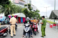 Lực lượng Công an tại chốt kiểm trên đường Phạm Văn Đồng (phường Hiệp Bình Chánh, Thủ Đức) kiểm tra giấy tờ của người lưu thông. (Ảnh: Thành Chung/TTXVN)
