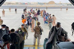 Người dân được lực lượng an ninh hỗ trợ lên máy bay sơ tán khỏi Afghanistan, tại sân bay quốc tế ở Kabul. (Ảnh: REUTERS/TTXVN)