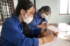 Em Vi Thị Hồng (19 tuổi, xã Đăk Hring, huyện Đăk Hà, tỉnh Kon Tum) viết đơn xung phong hỗ trợ tuyến đầu chống dịch COVID-19. (Ảnh: Khoa Chương/TTXVN)