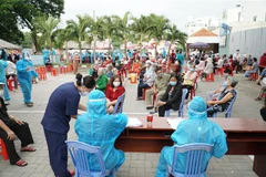 Nhân viên y tế hỗ trợ người dân tra cứu thông tin trước khi thực hiện tiêm chủng tại điểm tiêm UBND phường 9 (quận Gò Vấp, Thành phố Hồ Chí Minh). (Ảnh: Thu Hương/TTXVN)