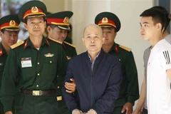  Lực lượng chức năng dẫn giải bị cáo Đinh Ngọc Hệ vào phiên xét xử. (Ảnh: Doãn Tấn/TTXVN)