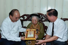 Chủ tịch nước Nguyễn Xuân Phúc đến thăm và tặng quà cho người có công. (Ảnh: Thống Nhất/TTXVN)