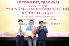 Ông Nguyễn Thế Kỷ, Chủ tịch Hội đồng Lý luận, phê bình văn học nghệ thuật Việt Nam (bìa phải) cùng ông Hồ Quang Lợi, Phó Chủ tịch Hội Truyền thông số Việt Nam trao giải Nhất cho tác giả Đan Nhiễm. (Ảnh: PV/Vietnam+)