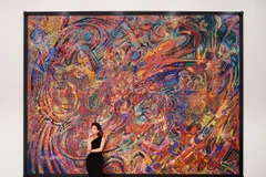 Họa sỹ CAT - Đào Anh Thơ với bức sơn mài nặng 250kg, tác phẩm đầu tiên trong series "Nước Mỹ bây giờ." (Ảnh: Lê Lai/Vietnam+ 