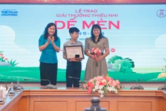 Phó Tổng giám đốc Thông tấn xã Việt Nam Nguyễn Thị Sự (trái) trao giải Khát vọng Dế Mèn cho tác giả Lê Sinh Hùng (giữa). (Ảnh: Minh Quyết/TTXVN)