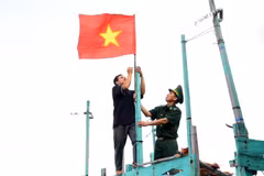 Cán bộ biên phòng giúp ngư dân treo cờ Tổ quốc lên tàu cá. (Ảnh: Hồng Đạt/TTXVN)