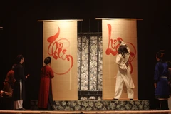 Cảnh Huấn Cao viết chữ trong tù được hình tượng hóa trên sân khấu kịch. (Ảnh: Minh Anh/Vietnam+)