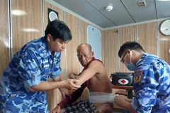 Cán bộ trên Tàu CSB 4035 băng bó, cấp cứu cho nạn nhân. (Ảnh: TTXVN phát)