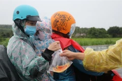 Một gia đình từ tỉnh Bình Dương được hỗ trợ phần cơm và trái cây miễn phí khi lưu thông qua tỉnh Phú Yên. (Ảnh: Phạm Cường/TTXVN)