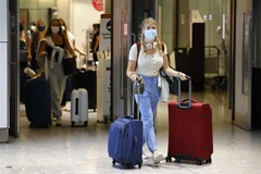 Hành khách đeo khẩu trang phòng lây nhiễm COVID-19 tại sân bay Heathrow, London, Anh. (Ảnh: AFP/TTXVN)
