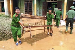 Các chiến sỹ công an huyện Hương Khê (Hà Tĩnh) chung tay dọn vệ sinh môi trường sau lũ tại xã Hương Đô. (Ảnh: Phan Quân/TTXVN)