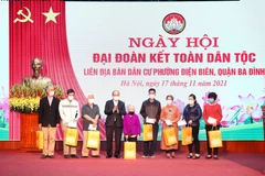 Chủ tịch nước Nguyễn Xuân Phúc trao tặng quà cho 8 hộ gia đình có hoàn cảnh khó khăn tại phường Điện Biên, quận Ba Đình. (Ảnh: Phạm Kiên/TTXVN)