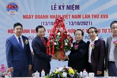 Đại sứ Nguyễn Bá Hùng đang trao lẵng hoa chúc mừng 17 năm ngày Doanh nhân Việt Nam cho ông Dương Đình Bảng, Chủ tịch lâm thời Hội doanh nghiệp Việt Nam hợp tác và đầu tư tại Lào. (Ảnh: Phạm Kiên/Vietnam+)