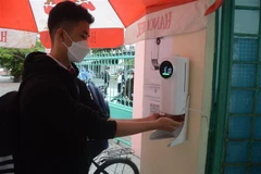 Học sinh đo thân nhiệt và rửa tay bằng nước sát khuẩn tại cổng trường. (Ảnh minh họa. Nguồn: TTXVN)