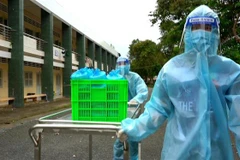 Điều dưỡng ở cơ sở cách ly Ký túc xá A, Đại học Cần Thơ mang cơm đến cho người dân đang cách ly. (Ảnh: Thu Hiền/TTXVN)