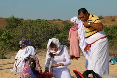 Chuẩn bị đồ cúng và mặc đồ truyền thống để thực hiện Lễ tảo mộ. (Ảnh: Nguyễn Thanh/TTXVN)