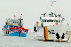 Tàu KN 322 thuộc Chi đội Kiểm ngư số 3 lai dắt tàu cá bị nạn cùng 19 ngư dân vào bờ an toàn. (Ảnh: Đức Thọ/TTXVN)