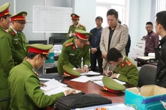 Lực lượng chức năng khám xét nơi ở, nơi làm việc của các đối tượng. (Ảnh: Võ Dung/TTXVN)
