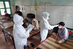 Nhân viên y tế đo thân nhiệt, kiểm tra sức khỏe đối với công nhân phải cách ly. (Ảnh: Dương Chí Tưởng/TTXVN)