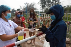 Nhân viên y tế chốt kiểm soát số 1 xã Sơn Lôi xịt khử khuẩn tiền trước khi thanh toán giao nhận hàng qua chốt kiểm soát số 1 tại xã Sơn Lôi. (Ảnh: Hoàng Hùng/TTXVN)