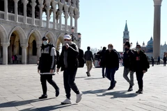 Du khách đeo khẩu trang phòng lây nhiễm COVID-19 tại Italy. (Ảnh: AFP/TTXVN)