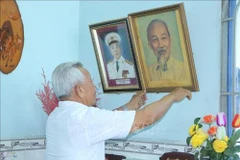 Ông Năm Dân bên ảnh bàn thờ Bác Hồ. (Ảnh: TTXVN)
