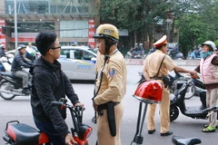 Cảnh sát giao thông tiến hành dừng xe, nhắc nhở học sinh phải đội mũ bảo hiểm khi tham gia giao thông. (Ảnh: Doãn Tấn/TTXVN)