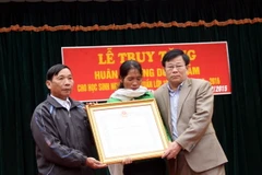 Ông Thái Huy Vinh (phải) trao Huân chương Dũng cảm của Chủ tịch nước cho đại diện gia đình em Nguyễn Anh Tuấn. (Ảnh: Tá Chuyên/TTXVN)