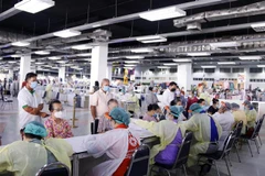 Các nhân viên y tế tại một điểm tiêm ở thủ đô Vientiane kiểm tra tiền sử bệnh lý của người dân trước khi tiêm vaccine. (Ảnh: Phạm Kiên/TTXVN)