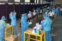 Các y bác sỹ Trung tâm kiểm soát bệnh tật Thành phố Hồ Chí Minh và Quận 7 thực hiện xét nghiệm sàng lọc COVID-19 ngẫu nhiên cho công nhân ở Khu chế xuất Tân Thuận. (Ảnh: Thanh Vũ/TTXVN)