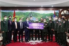 Phó Thủ tướng, Bộ trưởng Quốc phòng Lào trao số tiền 200.000 USD ủng hộ Quỹ phòng, chống COVID-19 của Việt Nam cho Đại sứ Việt Nam tại Lào Nguyễn Bá Hùng. (Ảnh: Phạm Kiên/TTXVN)