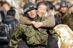 Binh sĩ Nhật Bản hỗ trợ người dân sơ tán tới nơi an toàn sau động đất tại thành phố Kesennuma, quận Miyagi ngày 12/3. (Nguồn: THX/TTXVN) 