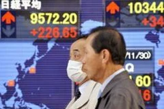 Hai thương gia đi ngang qua bảng giá cổ phiếu ở Tokyo ngày 1/12. (Ảnh: Daylife)