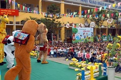 Cán bộ truyền thông hướng dẫn các em cách sử dụng tiết kiệm bao bì đựng sữa. (Ảnh: Dương Ngọc/TTXVN) 