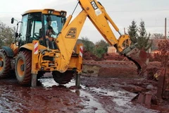 Xúc bùn ra khỏi nhà. (Nguồn: AFP/TTXVN)