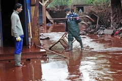 Hai người đàn ông đi chuyển trong bùn loãng nhiễm hóa chất độc ở ngôi làng Devecser, phía Tây Nam Budapest. (Nguồn: CNN) 