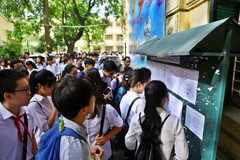 Thí sinh xem số báo danh và phòng thi tại điểm thi trường Trung học phổ thông Việt Đức. (Ảnh: Minh Quyết/TTXVN)