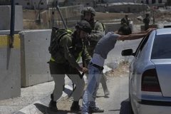 Binh sỹ Israel khám xét người dân Palestine tại một điểm kiểm soát ở trại tị nạn Fawwar ngày 16/8. (Nguồn: THX/TTXVN)