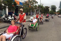 Khách du lịch nước ngoài thích thú khi chọn xíchlô làm phương tiện đi tham quan Đại Nội Huế. (Ảnh: Quốc Việt/TTXVN) 