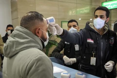 Nhân viên Cơ quan kiểm dịch Ai Cập kiểm tra thân nhiệt hành khách nhằm ngăn ngừa dịch viêm đường hô hấp cấp COVID-19 tại sân bay quốc tế Cairo. (Ảnh: AFP/TTXVN)