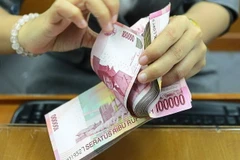 Một nhân viên đếm tiền giấy rupiah của Indonesia. (Nguồn: thestar)