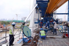 Công nhân thi công căng cáp trên phần cầu chính dự án cầu Thủ Thiêm 2. (Ảnh: TTXVN phát)
