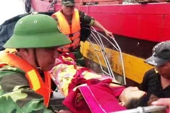 Lực lượng chức năng đưa người bị nạn vào bờ. (Ảnh: TTXVN phát)